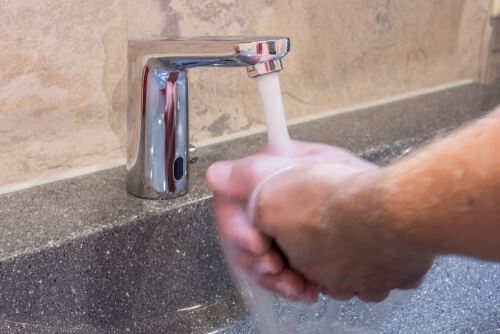 a person washing their hands using a touchless faucet